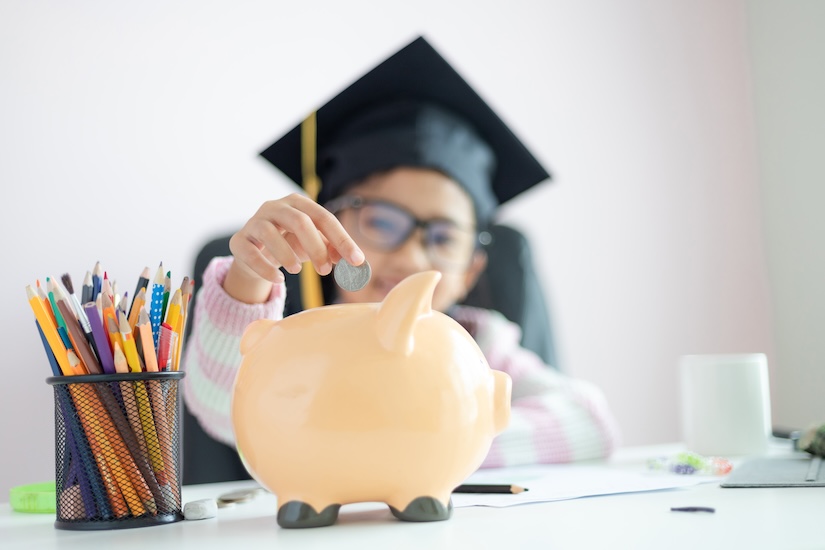 A girl putting the coin into a bank for future education